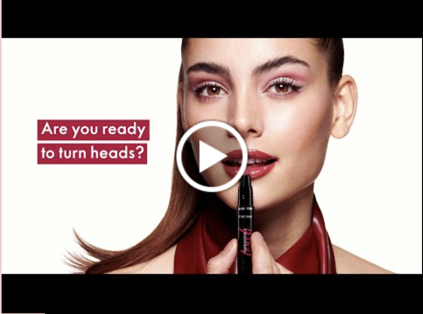 Cover image for the launch video for THE ONE Irresistible Touch High Shine Lipstick, featuring a woman applgin lisptick and the words 'Are you ready to turn heads?'